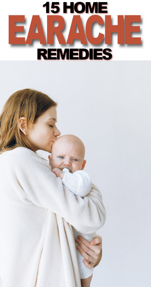 A young mother, wearing a white robe holding her baby who has an earache and kissing his head